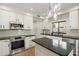 Bright kitchen features stainless steel appliances, white cabinetry, granite counters, and stylish pendant lighting at 4960 E Colonial Dr, Chandler, AZ 85249