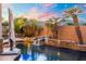 Resort-style pool featuring a beautiful rock waterfall, palm trees, and lush landscaping at 4960 E Colonial Dr, Chandler, AZ 85249