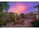 Private backyard featuring a fire pit, seating, and a beautiful desert landscape at dusk at 6939 S Red Hills Rd, Gold Canyon, AZ 85118