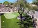 A well-manicured backyard with a small putting green, mature tree, and shade in this outdoor living space at 713 W Boxelder Pl, Chandler, AZ 85225