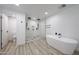 Bright bathroom featuring a glass enclosed shower, soaking tub and light wood-look floors at 7201 N 16Th Dr, Phoenix, AZ 85021