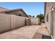 Concrete backyard area featuring tan privacy walls, a storage shed, and view of roofline of neighboring homes at 7344 E Flower Ave, Mesa, AZ 85208