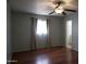 This cozy bedroom features wood floors, a ceiling fan, and a window with decorative curtains at 8334 N 55Th Ave, Glendale, AZ 85302