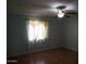 Bedroom featuring neutral walls, hardwood floors, ceiling fan, and a window with patterned curtains at 8334 N 55Th Ave, Glendale, AZ 85302