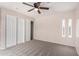 Carpeted bedroom with ceiling fan, sliding door closet with storage, and narrow windows at 9803 N 40Th Dr, Phoenix, AZ 85051