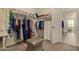 Spacious walk-in closet with shelving, drawers, carpet, and an ottoman for comfortable dressing at 10447 W Salter Dr, Peoria, AZ 85382