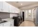 Well-organized laundry room with white cabinets, gray backsplash, modern black washer and dryer at 1502 E Treasure Cove Dr, Gilbert, AZ 85234