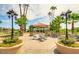 Charming outdoor seating area with a gazebo, tables, chairs, and beautiful landscaping with palms at 1502 E Treasure Cove Dr, Gilbert, AZ 85234