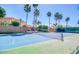 Well-maintained tennis court with a green and blue surface, surrounded by mature trees and greenery at 1502 E Treasure Cove Dr, Gilbert, AZ 85234