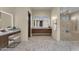 Elegant bathroom features a vanity with a lighted mirror, tiled floors, and walk-in shower with gold fixtures at 16119 N Desert Fox Pkwy, Fountain Hills, AZ 85268