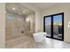 Bright bathroom featuring a modern soaking tub, a glass-enclosed shower, and black framed doors to the exterior at 16119 N Desert Fox Pkwy, Fountain Hills, AZ 85268