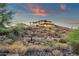 Expansive custom home on a hillside featuring multiple patios, stone accents, and breathtaking views during sunset at 16119 N Desert Fox Pkwy, Fountain Hills, AZ 85268