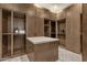 Spacious walk-in closet with custom wood shelving, drawers, and a center island with a light colored countertop at 16119 N Desert Fox Pkwy, Fountain Hills, AZ 85268