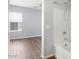 Bathroom with tub and shower combination, window, and wood-look flooring at 19664 W Woodlands Ave, Buckeye, AZ 85326