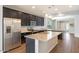 Spacious kitchen with stainless steel appliances, dark cabinets, and center island with breakfast bar at 19664 W Woodlands Ave, Buckeye, AZ 85326