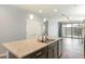 Modern kitchen island with stainless steel sink, stone countertops, and a view of the living room at 19664 W Woodlands Ave, Buckeye, AZ 85326