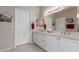 Bright bathroom featuring double sinks with white cabinetry and framed mirror at 19722 N Regents Park Dr, Surprise, AZ 85387