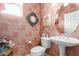 Charming powder room featuring a pedestal sink, ornate mirror and floral wallpaper at 19722 N Regents Park Dr, Surprise, AZ 85387