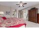 Bedroom features a walkout balcony, ceiling fan, and armoire for storage at 19722 N Regents Park Dr, Surprise, AZ 85387