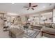 Large living room with neutral tones, open to the kitchen and dining area, featuring tile flooring and a ceiling fan at 19722 N Regents Park Dr, Surprise, AZ 85387