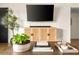 Close up on rattan cabinet beneath a wall-mounted television with decorative plants on the coffee table at 2418 E Hermosa Dr, Tempe, AZ 85282