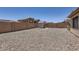 Large gravel backyard featuring a storage shed and a tall brick wall offering ample space and privacy at 24229 W Tonto St, Buckeye, AZ 85326