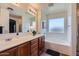 Bathroom with dual sink vanity, soaking tub, and large mirror at 24229 W Tonto St, Buckeye, AZ 85326