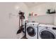 A bright laundry room features a modern washer and dryer with convenient storage shelves and utility equipment at 24229 W Tonto St, Buckeye, AZ 85326