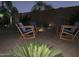 Outdoor patio featuring chairs arranged around a paver patio at night, complimented by green foliage and palm trees at 30178 N Coral Bean Dr, San Tan Valley, AZ 85143