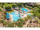 Expansive community pool area featuring a water slide, palm trees, and ample seating under shaded canopies at 30374 N 124Th Dr, Peoria, AZ 85383