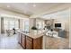 Open kitchen with granite island, stainless sink, view to dining room, and fireplace in living room at 30374 N 124Th Dr, Peoria, AZ 85383