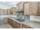 Kitchen featuring granite countertops, stainless hood, tile backsplash, and built-in gas range cooktop at 30374 N 124Th Dr, Peoria, AZ 85383