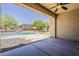 Covered patio view featuring a sparkling swimming pool, lush greenery, and a putting green at 30374 N 124Th Dr, Peoria, AZ 85383