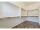 Large walk-in closet with built-in shelves and dark wood floors at 30374 N 124Th Dr, Peoria, AZ 85383