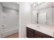 Bathroom featuring a shower-tub combo, vanity with dark wood cabinets, and large mirror at 3822 E Amber Ln, Gilbert, AZ 85296