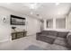Cozy living room featuring a plush gray sofa, neutral carpet, decorative shelving, and a mounted TV at 3938 E Appaloosa Rd, Gilbert, AZ 85296