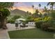 Lush backyard with manicured greenery, patio seating, vibrant flowers, and mountain views at 4836 E Moonlight Way, Paradise Valley, AZ 85253