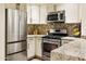 Modern kitchen featuring stainless steel appliances, stylish backsplash, and light-colored cabinets at 4836 E Moonlight Way, Paradise Valley, AZ 85253