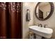 Charming bathroom featuring a pedestal sink, decorative mirror, and brown patterned shower curtain at 6160 S Pebble Beach Dr, Chandler, AZ 85249