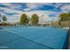 Community tennis courts with vibrant blue surface, surrounded by lush greenery and clear blue skies at 6160 S Pebble Beach Dr, Chandler, AZ 85249
