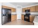 An efficient kitchen featuring wood cabinets, black appliances, and durable tile flooring at 11139 W Devonshire Ave, Phoenix, AZ 85037
