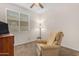 Cozy bedroom featuring a comfortable recliner, soft lighting, and a window with blinds for privacy at 11159 E Sebring Ave, Mesa, AZ 85212