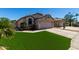 Single-story home with a two-car garage, desert landscaping, artificial turf, and a spacious driveway at 15231 W Melissa Ln, Surprise, AZ 85374