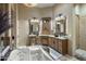 Open bathroom with dual vanities, a soaking tub, and elegant mirrors and lighting fixtures at 18036 W San Miguel Ave, Litchfield Park, AZ 85340
