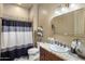 This bathroom features a vanity with granite countertop, a sink, and a shower with patterned curtain at 18036 W San Miguel Ave, Litchfield Park, AZ 85340