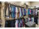 This walk-in closet features ample storage with shelves, hanging rods, and a patterned ottoman in a neutral color palette at 18036 W San Miguel Ave, Litchfield Park, AZ 85340