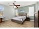 This bedroom features neutral walls, wood flooring, a ceiling fan, and bedside tables with lamps at 18242 W Stinson Dr, Surprise, AZ 85374