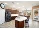 Island kitchen with stainless appliances, dark wood cabinets, and an adjacent dining area and pool view at 18242 W Stinson Dr, Surprise, AZ 85374
