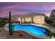Inviting backyard with a sparkling blue pool, covered patio, and desert landscaping perfect for outdoor relaxation and entertainment at 18242 W Stinson Dr, Surprise, AZ 85374