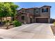 Two-story stucco home featuring a three-car garage, mature landscaping, and a tiled roof at 19427 W Colter St, Litchfield Park, AZ 85340